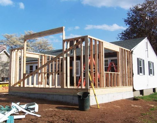 Contemporary home addition with large glass windows and wood exterior accents by Prime Built.