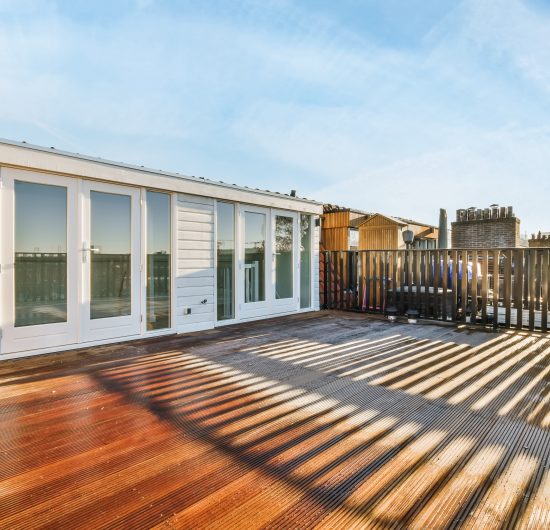 Modern wooden backyard deck with outdoor seating and decorative railing.