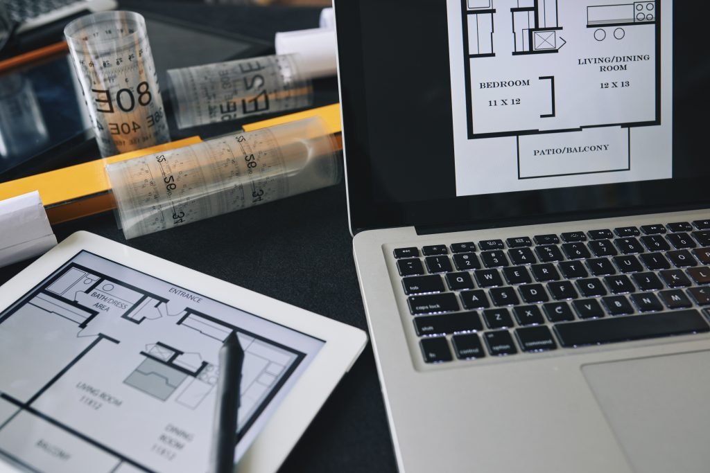 Architect’s hands sketching a detailed house design on paper with drafting tools.